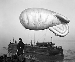 A kite balloon tethered to the balloon barge NORMAN WADE on the River Humber, at No. 17 Balloon Centre at Sutton-on-Hull in Yorkshire, January 1943.