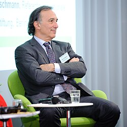 Peter Seligmann speaking at a lectern during a conference in Berlin.
