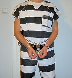 Inmate in striped prison uniform and restraints