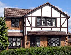 "A modern Tudorbethan" house with uPVC gutters and downspouts, fascia, decorative imitation "half-timbering", windows, and doors