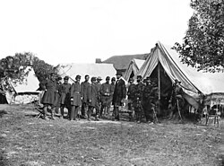 Lincoln among a group of soldiers in a military camp