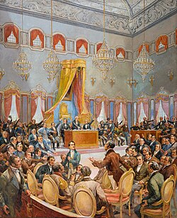 A large historical painting shows a crowded parliamentary chamber in the middle of a heated debate during the Constituent Cortes of 1820. Dozens of formally dressed men gesture, argue, and rise from their seats beneath towering crystal chandeliers and a richly decorated ceiling, while officials sit at a central desk below a grand canopy and throne.