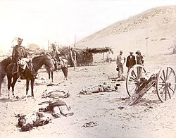 Martiniano Urriola, with kepi, the commander of the occupation of Ayacucho in 1883, and Marcos Maturana, with poncho, the general chief of staff chief of the Expeditionary Army during the Lima Campaign; they view the dead bodies of a Peruvian gun crew after the Battle of Chorrillos.