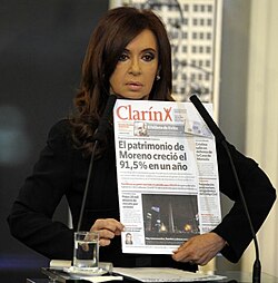 President Cristina Fernández holding a copy of Clarín in 2012. She and her late husband Néstor Kirchner had a long-standing conflict with the newspaper, which included "anti-Clarín" propaganda
