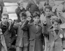 Children preparing for evacuation during the Spanish Civil War (1930s), some giving the Republican salute. The Republicans showed a raised right fist whereas the Nationalists gave the Roman salute.[9]