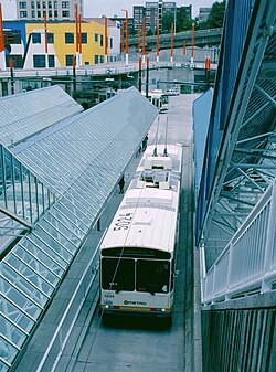 A trolleybus seen at a below-grade station with long glass shelters