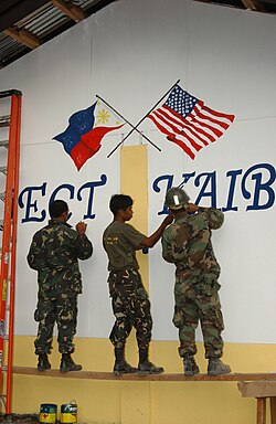 Filipino soldiers painting a U.S. and Philippine flag