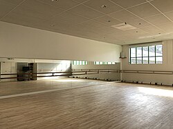Dance studio with barre rails, mirrors, and mounted speakers