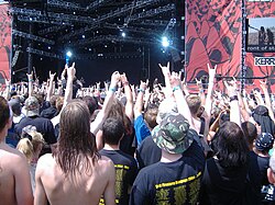 Fans raise their fists and make the "devil horns" gesture at a concert
