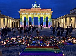 Flowers and candles at Pariser Platz in front of the Brandenburg Gate one day after the attack. The Brandenburg Gate is illuminated in Pride colors.