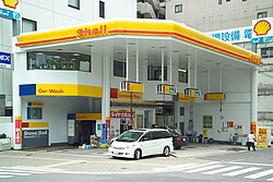 Like many gasoline stands in Japan, this Shell filling station has hoses that hang from above.