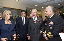 Charles and two men in suits and uniforms with Camilla in a blue dress stand as they are engaged in conversation.