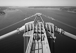 A thick steel cable passing over the top of a suspension bridge tower