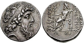 Coin of Demetrius II. The reverse shows Zeus bearing Nike. The Greek inscription reads ΒΑΣΙΛΕΩΣ ΔΗΜΗΤΡΙΟΥ ΘΕΟΥ ΝΙΚΑΤΟΡΟΣ, i.e. "of God King Demetrius, the Victor ". The date ΔΠΡ is year 184 of the Seleucid era, corresponding to 129–128 BC.