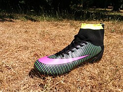 A football boot based upon a common design used in 2018. Note the absence of a leather tongue, the relatively low rear upper around the heel, and the presence of a sock style fastener. This design helps to ensure maximum flexibility and range of movement. By limiting the potential impingement of the ankle joint by the boot upper, it allows the wearer's gait to be more natural.