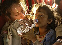 An American soldier gives a young Pakistani girl a drink of water as they are airlifted from Muzaffarabad to Islamabad following the 2005 Kashmir earthquake.