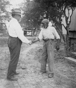 Musicologist John Lomax (left) shaking hands with musician "Uncle" Rich Brown in Sumterville, Alabama