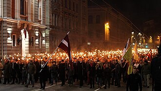 18th November Torch Procession [lv] in 2013, originally organised by All for Latvia! and later taken over by the National Alliance, with All for Latvia! leader Raivis Dzintars carrying the flag of Latvia at the front