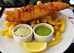 Fish and chips, a traditional British dish, served with lemon, tartar sauce and mushy peas