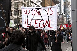 Anarchist protest in Australia with banner reading "no one is illegal"