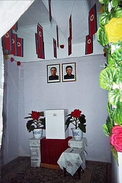 A North Korean voting booth containing portraits of Kim Il Sung and Kim Jong Il under the national flag (below the portraits is the ballot box)
