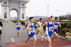 Participants in the 2015 Pyongyang Marathon running past the Arch of Triumph