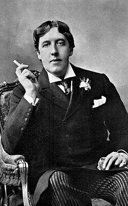 Oscar Wilde (1854–1900) wearing a frock coat with a chest pocket sporting a pocket square and a pinned cravat in a Ruche knot. Frock coats with any external pockets at all are a rarity.
