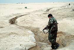 A Coalition soldier inspects an abandoned Iraqi trench for any remaining enemy soldiers during Operation Desert Storm