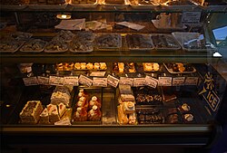 International desserts (e.g., chou à la crème, dobostorta, tiramisu, etc.) on display in a Timișoara store