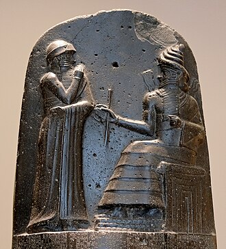 Hammurabi (standing), depicted as receiving his royal insignia from Shamash (or possibly Marduk). Hammurabi holds his hands over his mouth as a sign of prayer[10] (relief on the upper part of the stele of Hammurabi's code of laws).