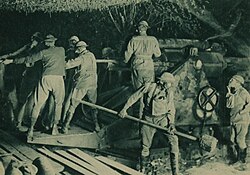 Australian gunners, wearing gas masks, operate a 9.2-inch (230 mm) howitzer during World War I