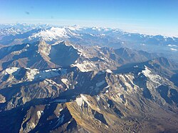 An aerial view of the Andes between Santiago in Chile and Mendoza, Argentina with a large ice field on the southern slope of San José volcano (left), Marmolejo (right), and Tupungato (far right).