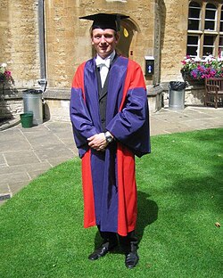 A doctor of philosophy of the University of Oxford, in full academic dress. The typical dress for graduation are gowns and hoods or hats adapted from the daily dress of university staff in the Middle Ages, which was in turn based on the attire worn by medieval clergy.[134]