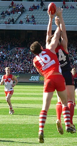 Sydney Swans player appears to chop the right arm of his Melbourne Demons opponent preventing a clean mark