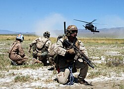 Pararescuemen and a simulated "survivor" watch as an HH-60G Pave Hawk helicopter comes in for a landing.