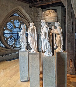 Four white statues of people on pedestals