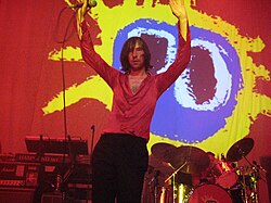 Primal Scream performing live with the cover of their album Screamadelica in the back