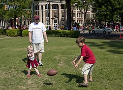 Timothy L. Pesto and Kaitlyn E. Pesto play football as their father watches, Tuscaloosa, Alabama.