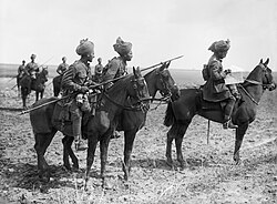 Three Indian horsemen in the foreground, the man on the left carries a lance a sergeant is in the middle and an officer on the right. In the background can be seen three further cavalrymen