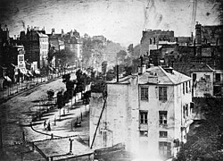 The earliest reliably dated photograph of people, View of the Boulevard du Temple was taken by Daguerre one spring morning in 1837 or 1838 from the window of the Diorama, where he lived and worked. It bears the caption huit heures du matin (translation: eight o'clock in the morning).[note 4]