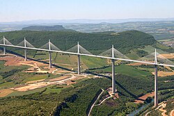 A large bridge, consisting of multiple tall sections, passing over a wide valley