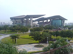 A far view of a stadium, with two large sitting pavilions and greenery around the compound.