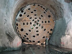 A workman is dwarfed by the cutting end of a tunnel boring machine used to excavate the Gotthard Base Tunnel (Switzerland), the world's longest railway tunnel.