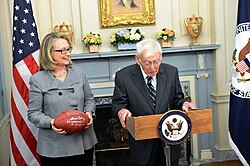 Rooney with Hillary Clinton, posing with an autographed game ball in 2013
