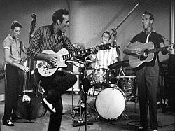 Perkins (front) performing "Glad All Over" with (left to right) Clayton Perkins, W.S. "Fluke" Holland, and Jay Perkins in the 1957 movie Jamboree