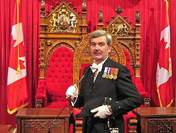 Kevin MacLeod, the former Canadian Usher of the Black Rod, stands in front of the 1878 Senate thrones