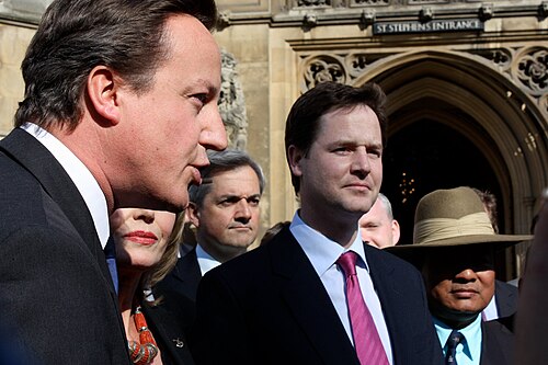 David Cameron and Nick Clegg outside the Houses of Parliament, with Huhne in the background