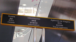 A multilingual sign at the Hong Kong-Macau Ferry Pier in Macau. At the top are Portuguese and Chinese, which are the official languages of Macau, while at the bottom are Japanese and English, which are common languages used by tourists (English is also one of Hong Kong's two official languages).