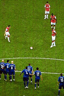 Often several players (red) will line up for a free kick, so as to mask their intentions to the defending team (blue).