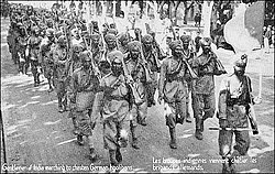 The 15th Sikh Regiment arrive in Marseille, France, on their way to fight the Germans during the First World War. The post card reads, "Gentlemen of India marching to chasten German hooligans"